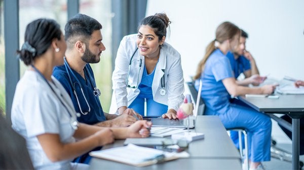 Premed Lecture Series: Students wearing scrubs and white coat in a classroom