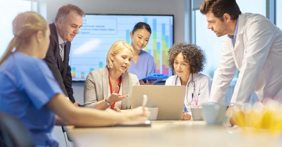 Medical and business professionals in a conference room reviewing data