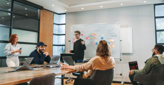 Diverse colleagues collaborating in a modern boardroom, working on projects and discussing ideas as a tech team