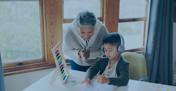 Instructor praising child with headphones while coloring