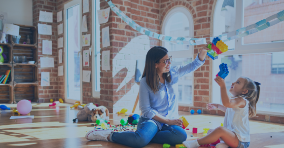 Child playing with building blocks with female teacher
