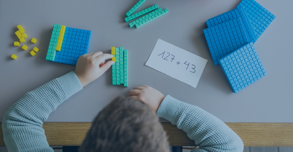 Little boy using the base 10 method to do addition at home