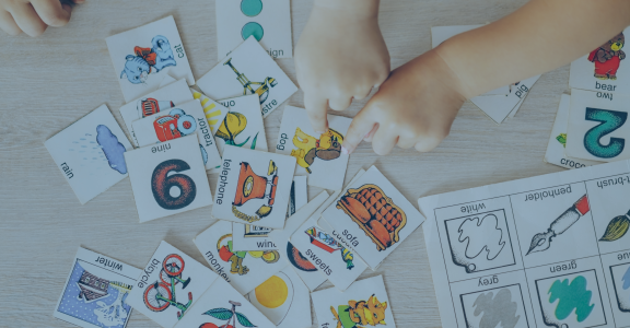 Children hands touching white cards of letters numbers and pictures for little kids on table