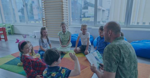 teacher reading a book to a group of students in a circle on a rug