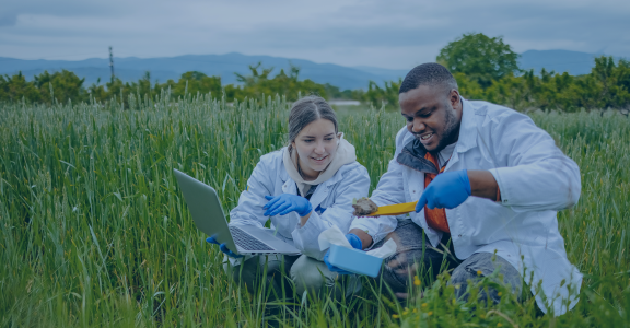 Two scientists in the field looking at dirt specimen