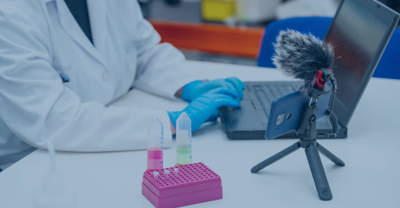 Scientist sitting down with laptop and recording on phone