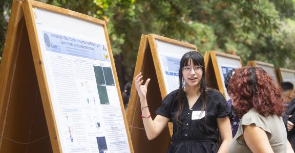 Student presenting research poster to another person