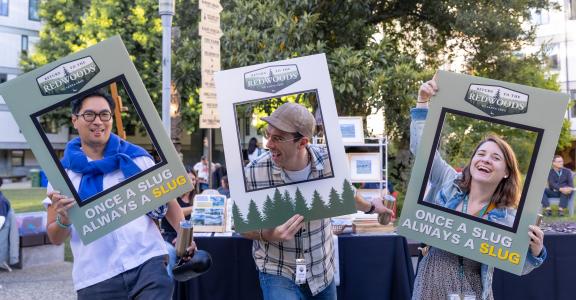 Three UCSC alumni posing in a photo frame for Return to the Redwoods event