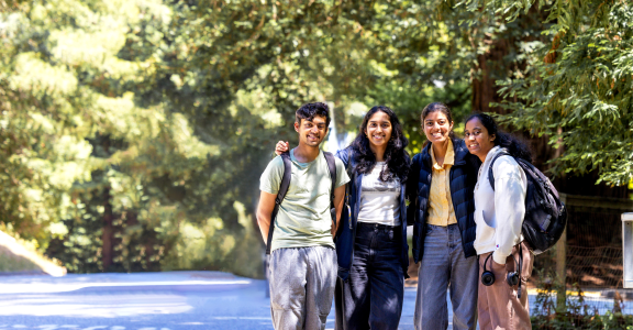 group of 4 students posing in front of trees