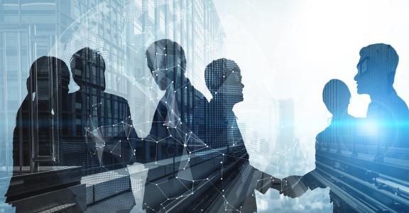 Silhouette of business people shaking hands in city office building background.