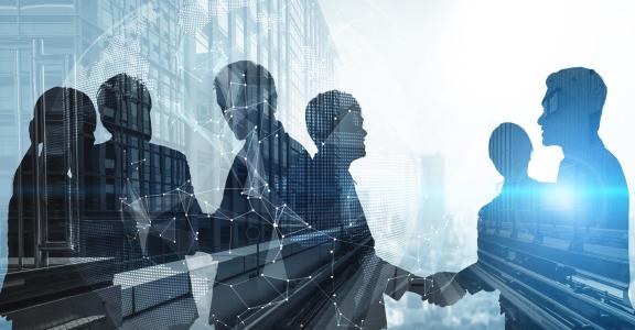 Silhouette of business people shaking hands in city office building background.