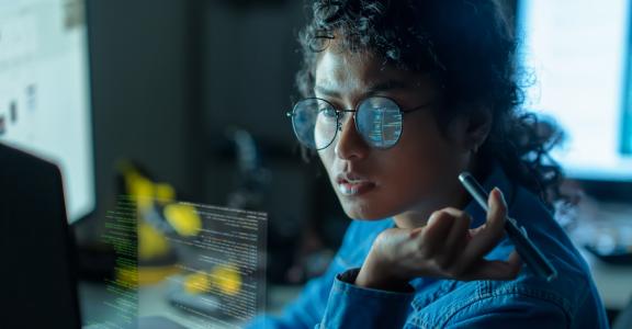 Asian woman collaborates on a SaaS platform, writing code on multiple screens in a vibrant coworking environment, driving technology forward.