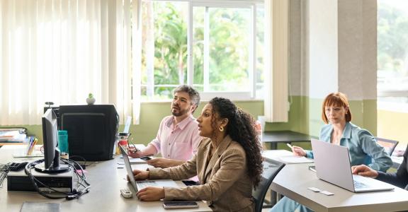 Female teacher giving lecture to adult students sitting in university classroom