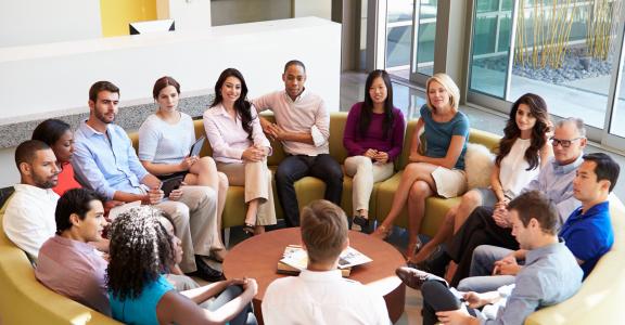 Multi-Cultural Office Staff Sitting Having Meeting Together In Smart/Casual Dresswear