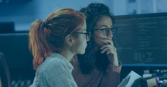 two women looking at computer screen with code
