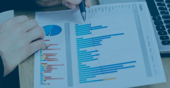 Person with pen and paper with different graphs