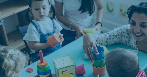 teacher with toddlers stacking shapes