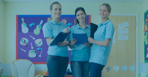 three women in blue shirts holding books