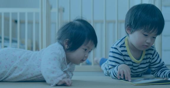 Two toddlers looking at a book