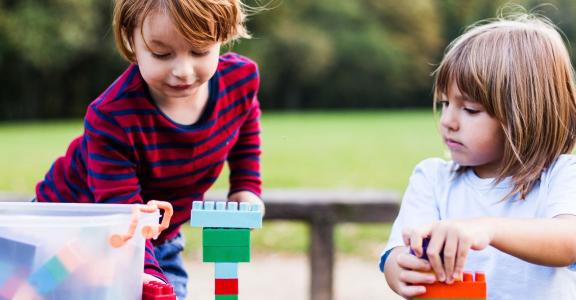 two young children outside playing with Legos