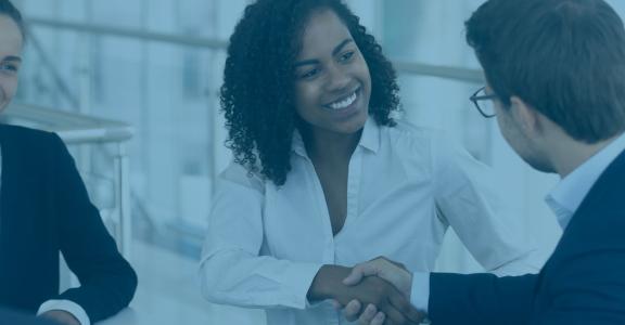 Two women smiling one shaking hands with man