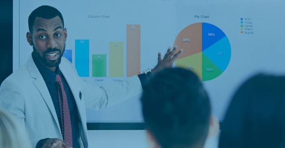 man pointing to colorful charts in front of a group of peopl