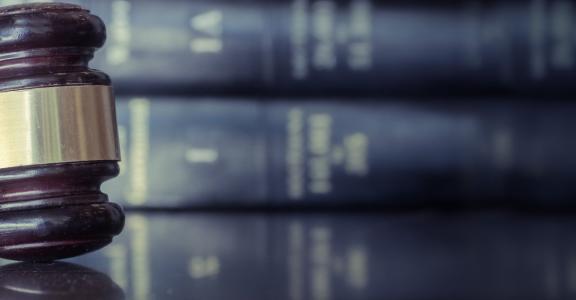 Judicial gavel on table with a background of law books