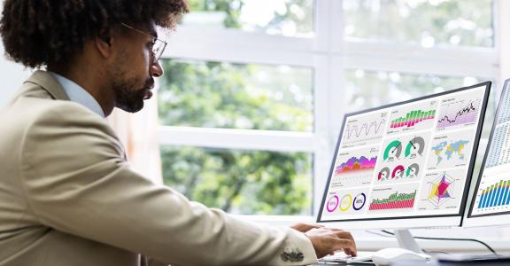 Business man at a desk looking at charts and data graphs on 