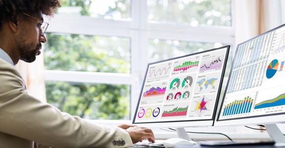 Business man at a desk looking at charts and data graphs on 