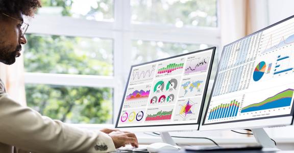 Business man at a desk looking at charts and data graphs on 