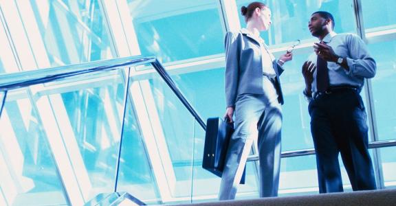 professional woman and man talking at the top of a staircase