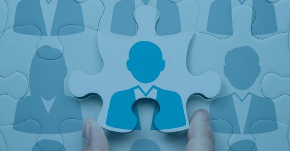 Hand holding puzzle of blue people outlines