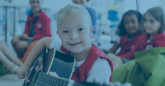 Young neurodivergent boy smiling with guitar