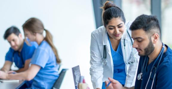 Teacher helping students in a medical school classroom