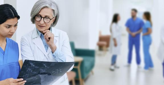 Female doctor looking at scans with a younger intern in a ho