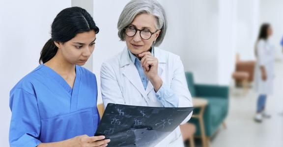 Female doctor looking at scans with a younger intern in a ho