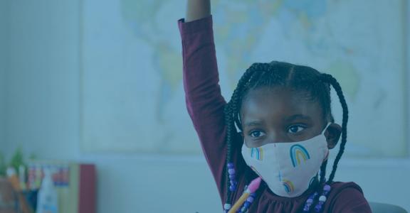 Young girl with face mask raising hand in class
