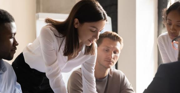 group of professionals sitting and standing around a table w