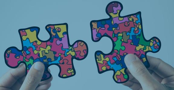 hands holding two colorful puzzle pieces