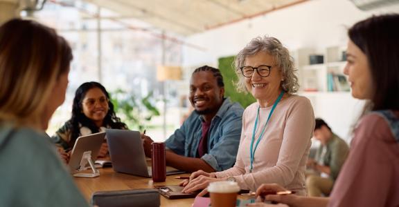 Happy mature professor and her students talking at university classroom.