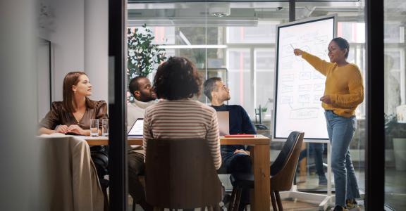 Project Manager Makes a Presentation for a Young Diverse Creative Team in Meeting Room in an Agency.