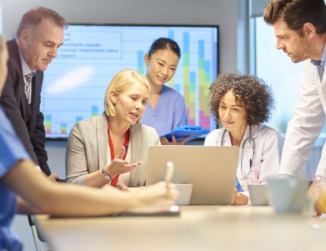 Medical and business professionals in a conference room reviewing data