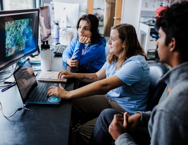 3 high school students collaborating on a marine science project at a computer