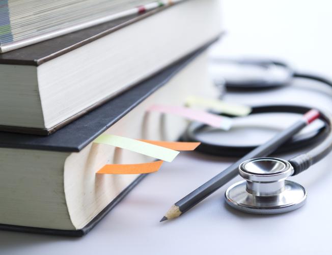 Medical student textbooks with pencil and multicolor bookmarks and stethoscope isolated on white