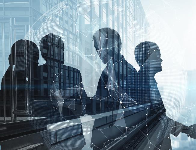 Silhouette of business people shaking hands in city office building background.