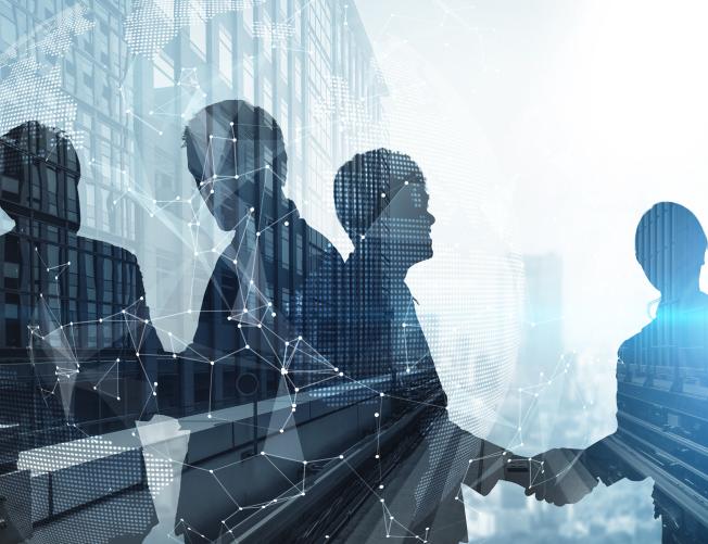 Silhouette of business people shaking hands in city office building background.