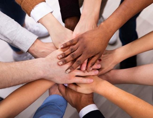 hands of different colors and genders meeting in the center 