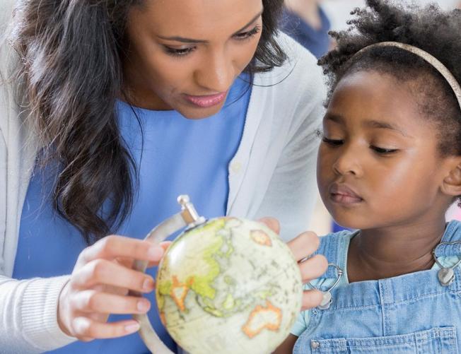 teacher showing young child a globe of the world