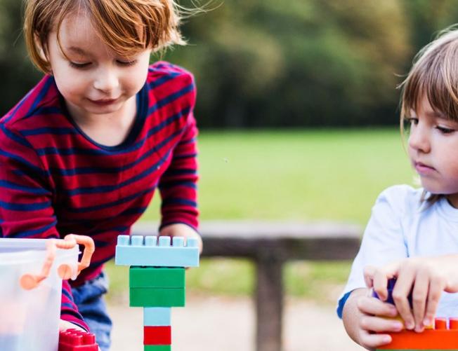 two young children outside playing with Legos