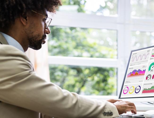 Business man at a desk looking at charts and data graphs on 